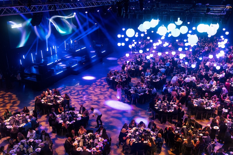 Corporate awards night and gala dinner production at the Viaduct Events Centre featuring custom lighting design and large round banquet tables.
